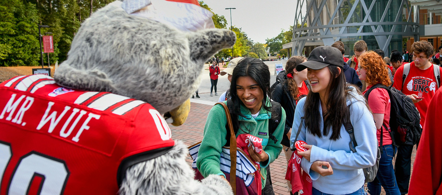 NC State students smile a they meet the university mascot, Mr. Wuf.